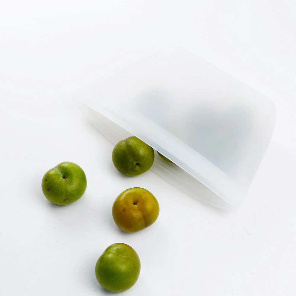 White silicone food-storage pouch shown from above beside green fruit