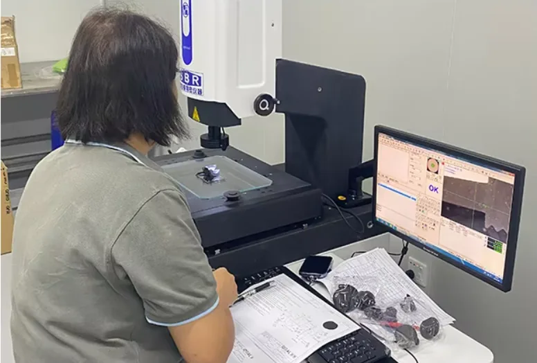 Operator using a dimensional measuring instrument beside a computer